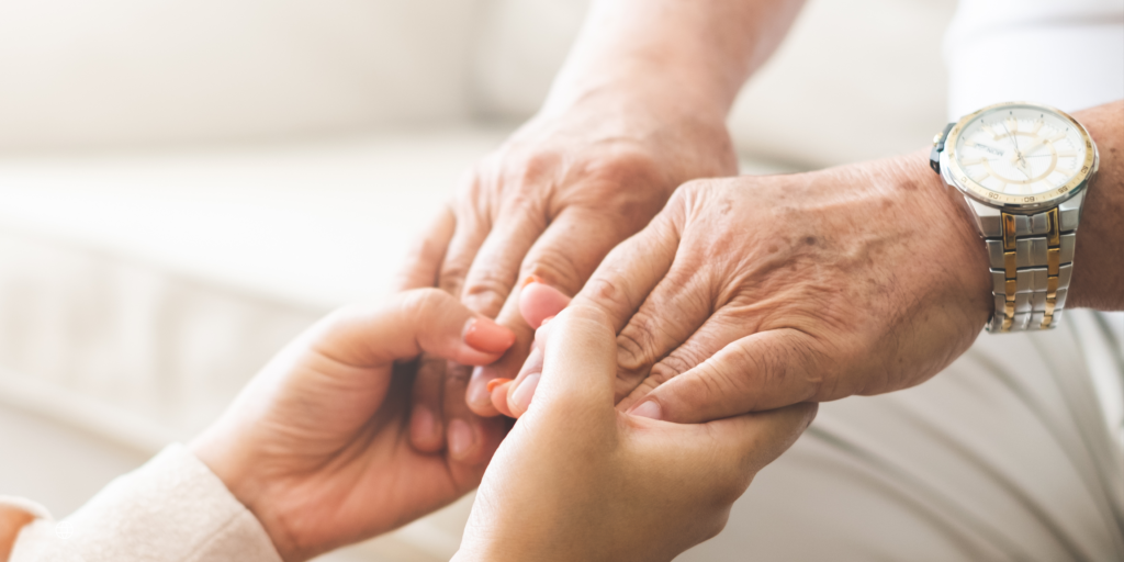 aging parent holding the hands of his daughter to represent joint Tenancy and joint Ownership