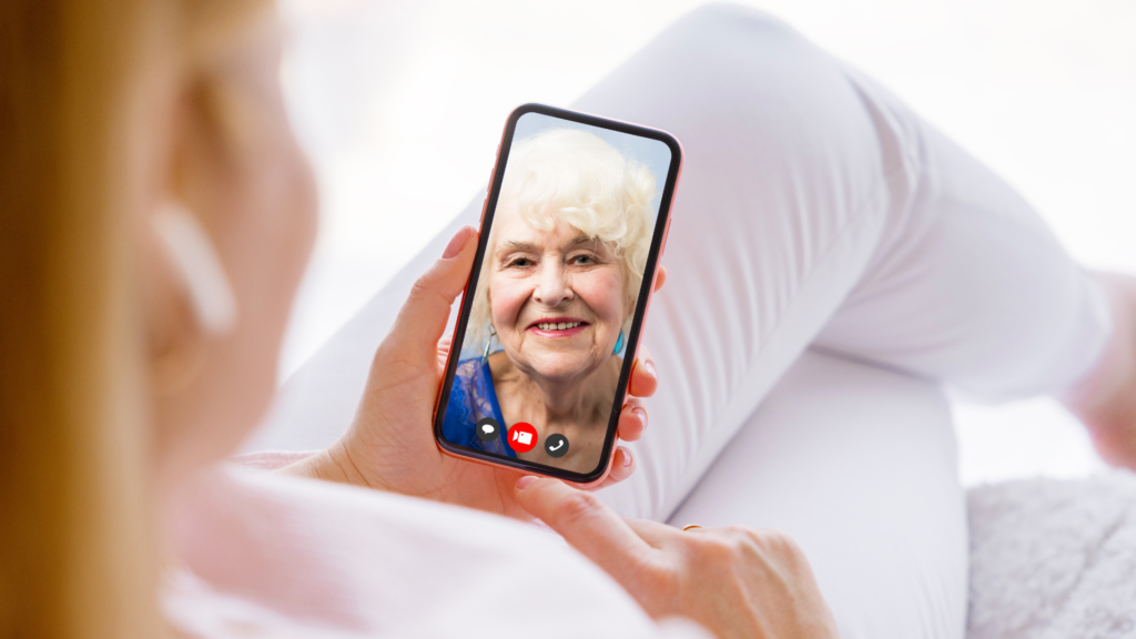 woman holding a phone with her elderly mother to ensure she is caring for her aging parent at a distance